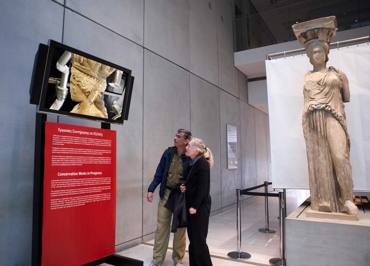 Visitors watching the video showing conservators do the delicate work of cleaning the Caryatids with advanced laser technology. © Acropolis Museum. Photo: Giorgos Vitsaropoulos.
