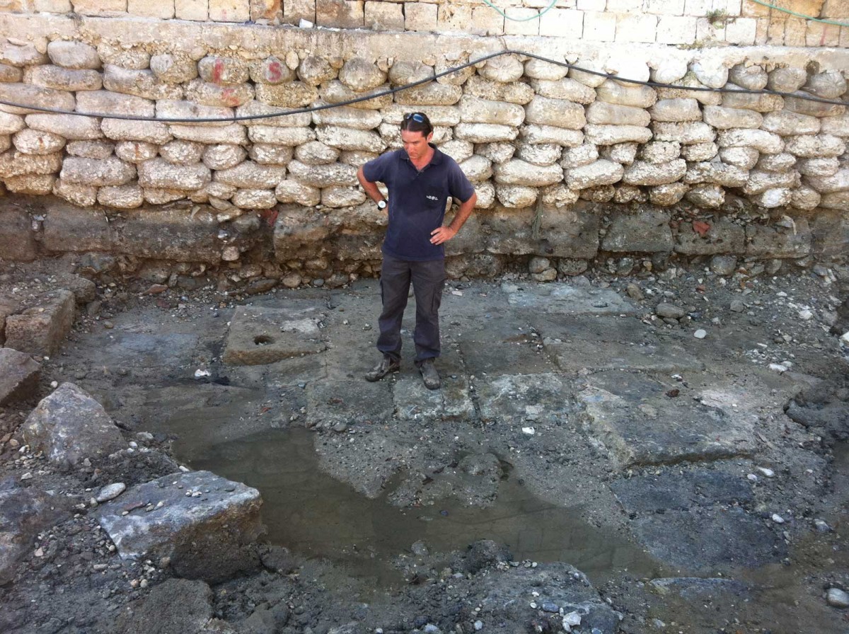 A member of the Marine Archaeology Unit of the Israel Antiquities Authority standing on the ancient quay that was exposed in Akko. (Credit: Israel Antiquities Authority)