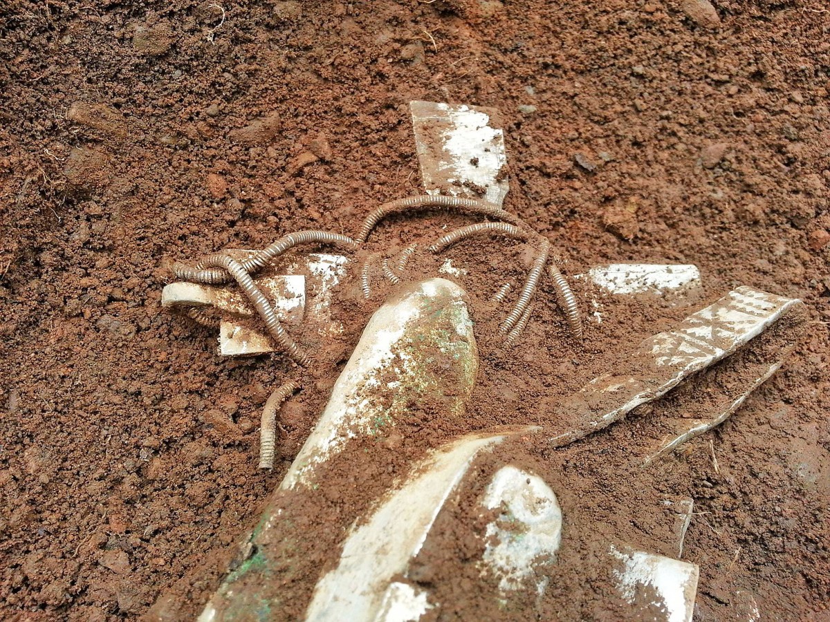 The silver cross, ingots and arm-rings are slowly revealed in the first level of the hoard, 24 inches underground. (Image: Derek McLennan.)