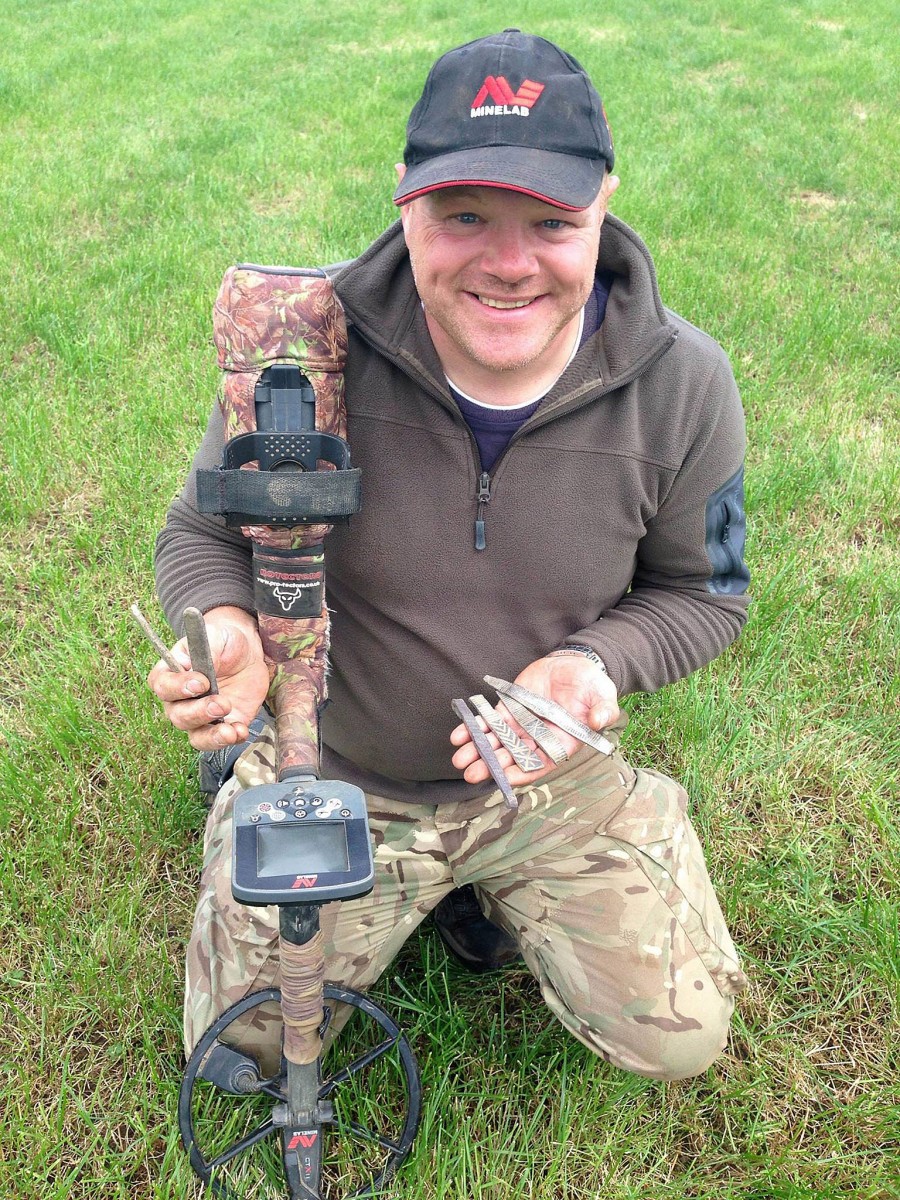 Derek McLennan with his MineLab metal detector holding the first silver ingots and arm-rings he discovered. (Image: Derek McLennan) 