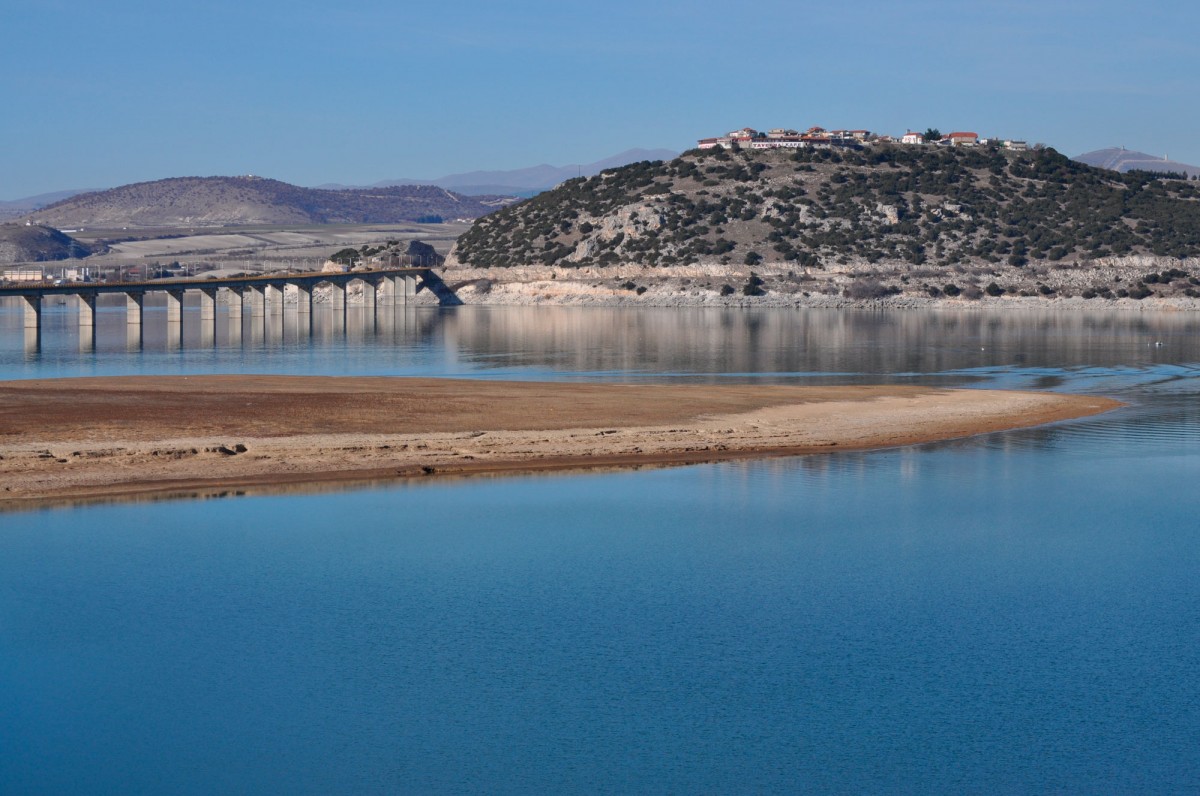 Fig. 1. Southeastern view of the hill of Neraida. On the top of the plateau is the Prehistoric and Hellenistic settlement and on the slope the cave. In the foreground the site of Kolitsaki and in the bottom of the lake, to the right of the bridge, the “prehistoric settlement of Servia”.