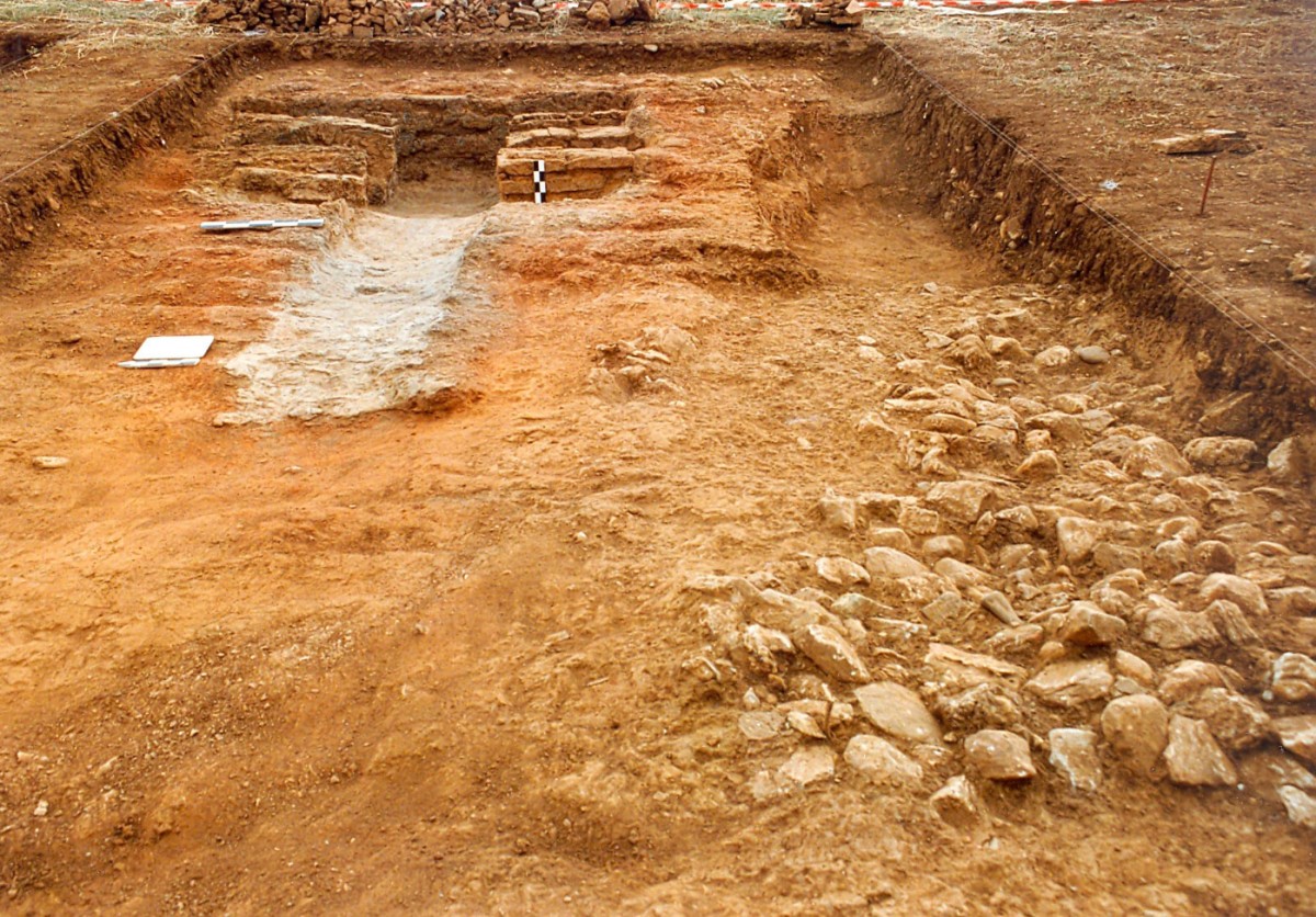 Fig. 4. Kampos Frourio, kiln of Roman times, constructed inside a rock cut circular grave with long entrance passage (dromos), of the beginning of the Early Iron Age. On the right, back-filled natural cavity, with stones and pot-sherds belonging to fragmented vessels-grave offerings.