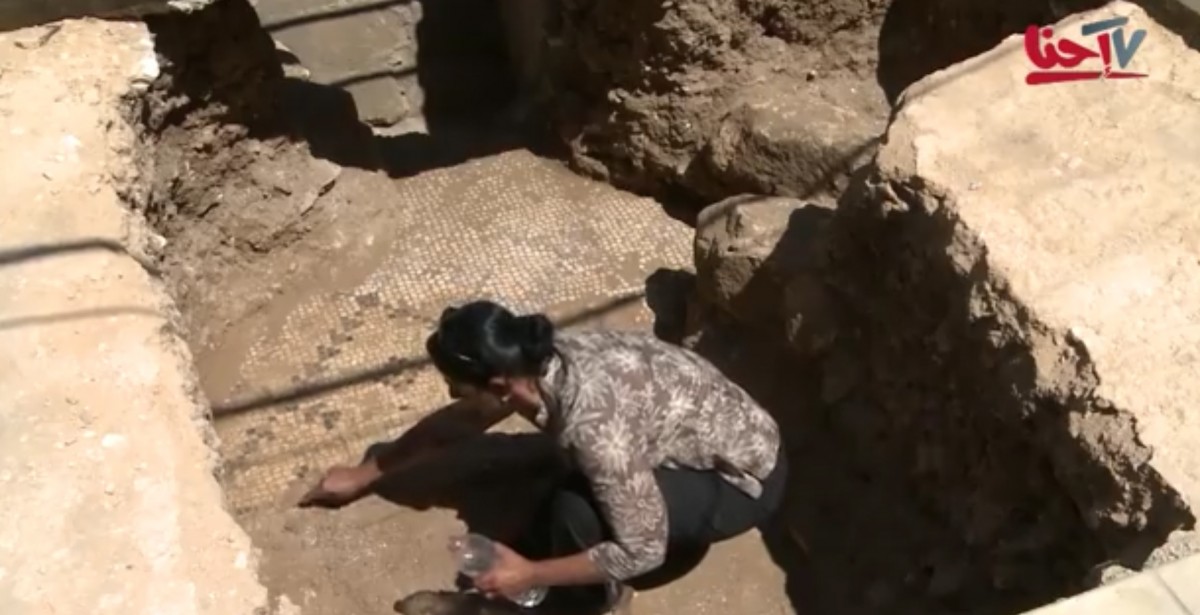 Cleaning the mosaic floor at the Church of the Annunciation. (Screenshot from coverage of the mosaic floor discovery on Arabic television).