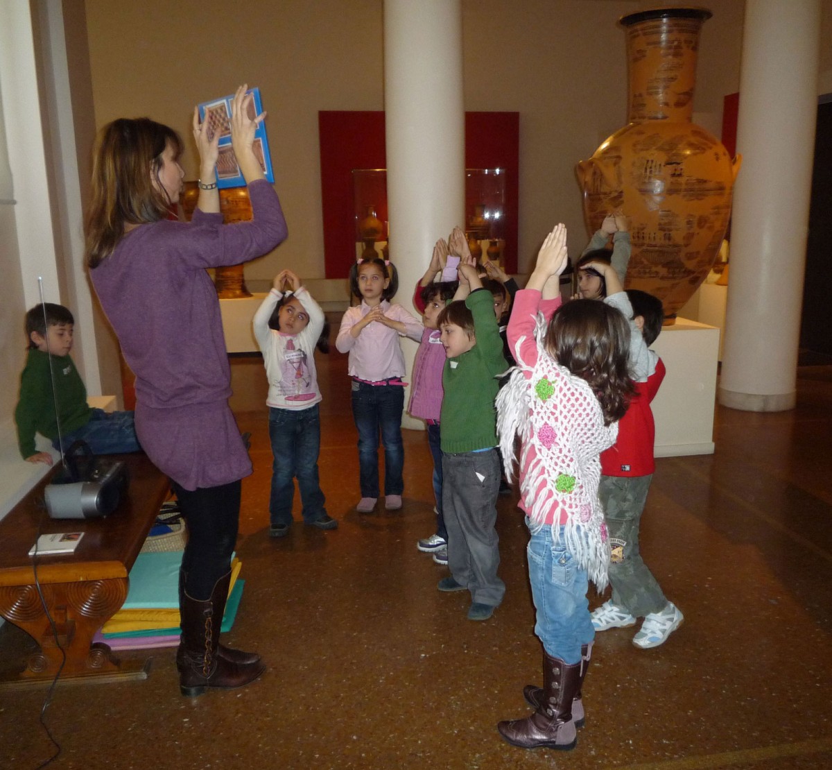 Fig. 1. Children dance to the rhythm of ancient Greek music based on geometric motifs shown to them by the museum educator and a choreography based on pre-arranged movements (Educational programme “The line trip in ancient times” Photographic Archive, National Archaeological Museum).