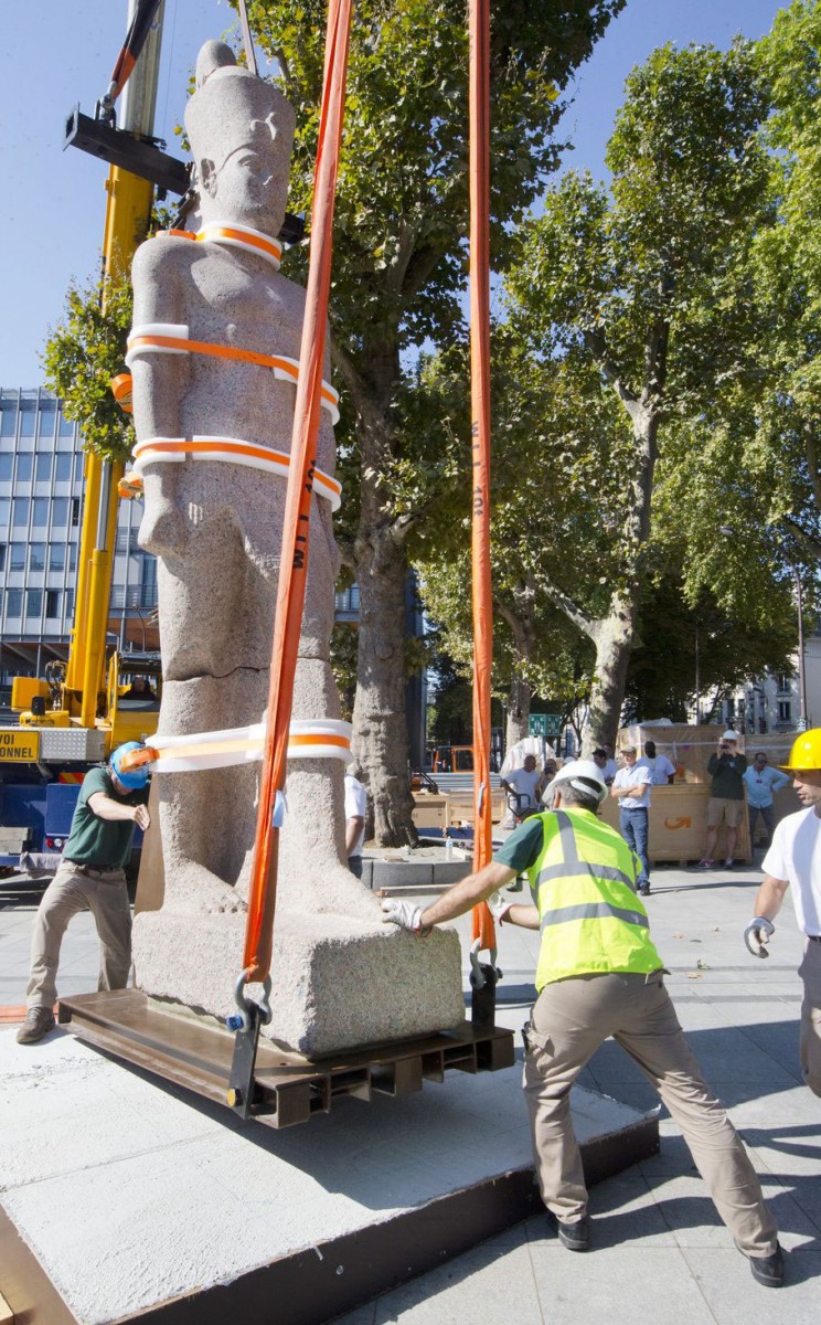 Workers set up a statue of an unnamed Egyptian king dating from the Ptolemy era, made of pink granite and measuring 5 meters and weighing 5.5 tons in Paris, France, Friday Aug. 21, 2015. Photo Credit: AP Photo/Jacques Brinon.