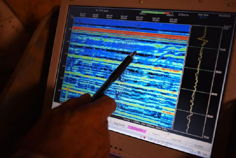 Pointing to his computer screen, Watanabe explains the multicolored bars that  represent radar data used to determine the material structure of the walls. Photo Credit: Brando Quilici/National Geographic.