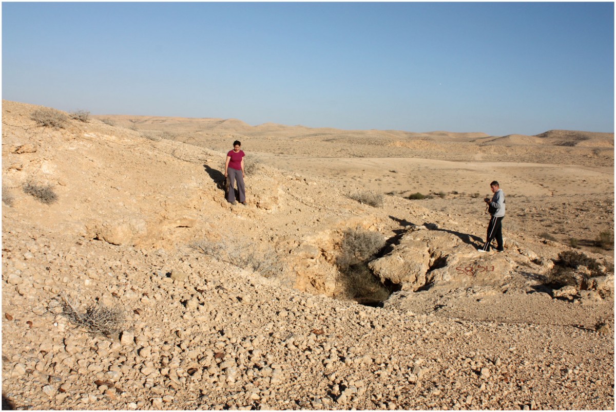 The vertical entrance to the cave is located in front of the standing figure. Photo Credit: PLOS ONE.