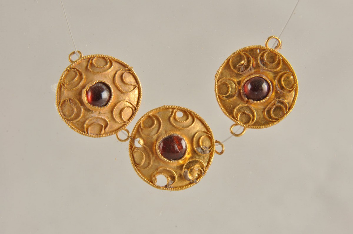 Fig. 37. Gold concave-convex discs inlaid with a semi-precious stone, flanked by six crescents of thin twisted wire. Costume jewellery. They were found in a tomb of the Hellenistic period in Chios town (Metropolis).