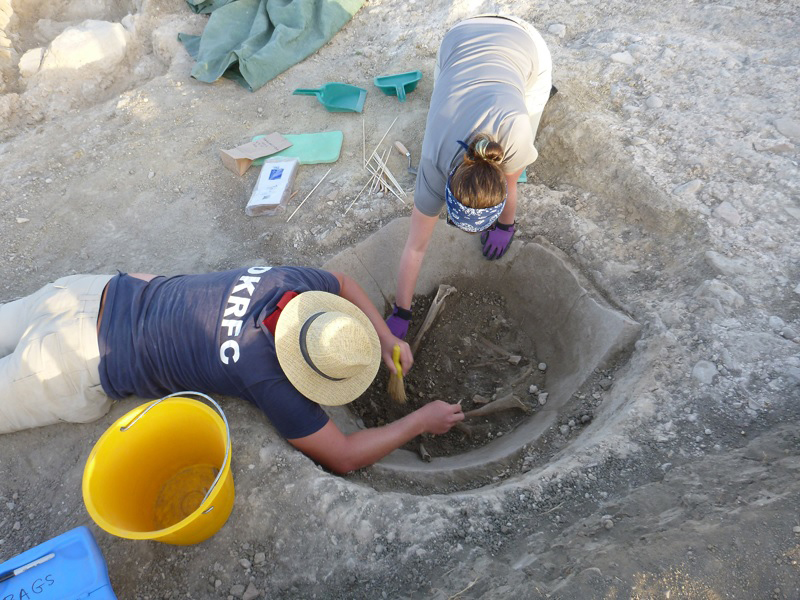 Excavating wine vat containing two human skeletons in its fill. Credit: M. Carroll.
