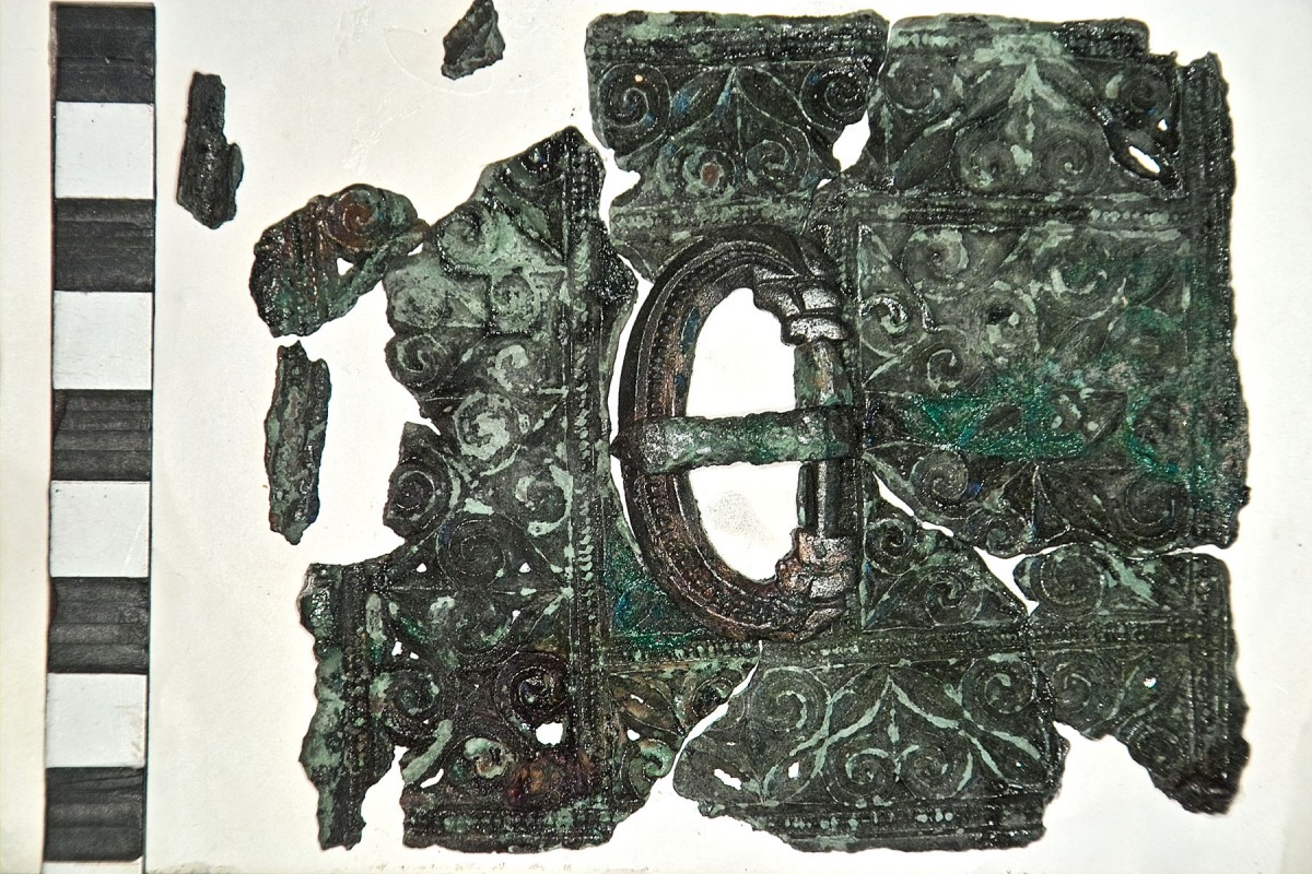 Fig. 7. The bronze belt plate is cast in the so-called ‘chip-carved’ style and would have been riveted to a wide leather belt or girdle with a thinner securing strap running through the buckle and ending with the strap end.