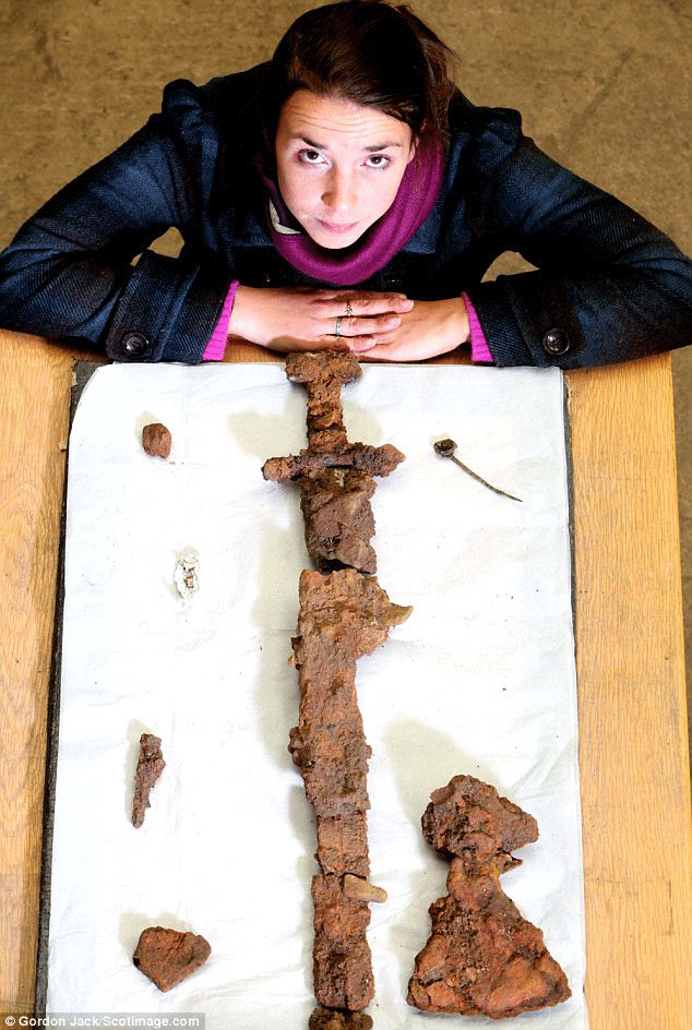 Helena Gray with the sword and other artefacts found in the grave. The Viking vessel the warrior was buried in has almost completely rotted away. Photo Credit: Daily Mail.