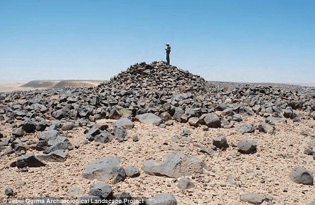 A typical hilltop cairn in the Jebel Qurma region, with its conical pile of basalt blocks (pictured), is explored by the researchers. Photo Credit: Jebel Qurma Archaeological Landscape Project.