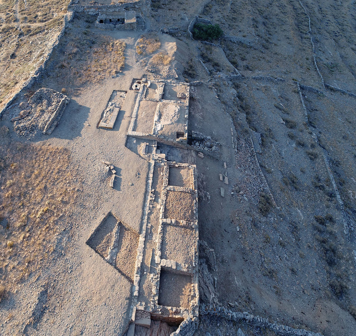 Fig. 17. Aerial photograph of the Ano Polis and Buildings 1 and 2 on the Middle Plateau, from the north. In the background the Acropolis with the sanctuary of Demeter. Photo Credit: Kostas Xenikakis. 