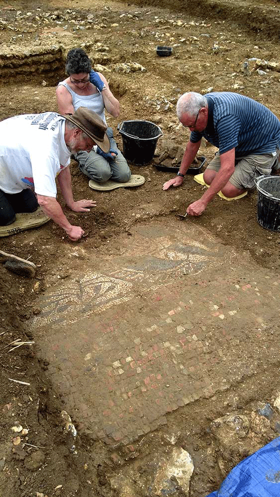 Volunteers cleaning the mosaic. Photo Credit: Cotswold Archaeology.