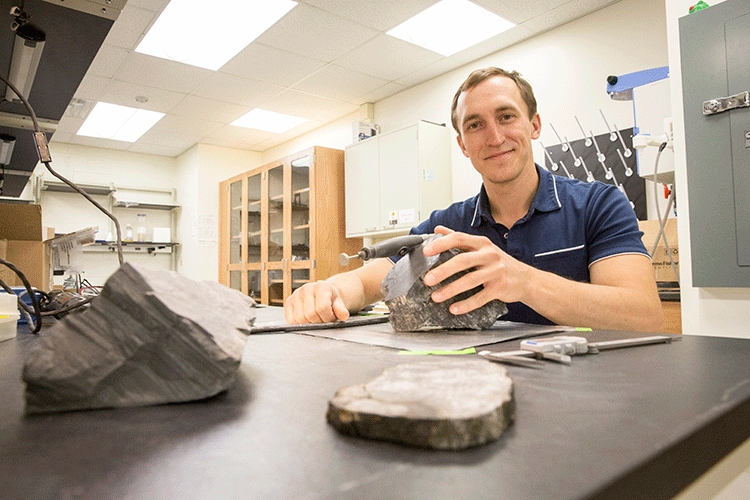 Erik Gulbranson, paleoecologist and visiting assistant professor at UWM, studies some of the fossilized trees he brought back from Antarctica. Gulbranson is returning there for further research this year. Photo Credit:UWM Photo/Troye Fox.