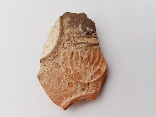 Oil lamp sherd decorated with a nine-branched menorah. Photo: Anat Rasiuk, Courtesy of the Israel Antiquities Authority)