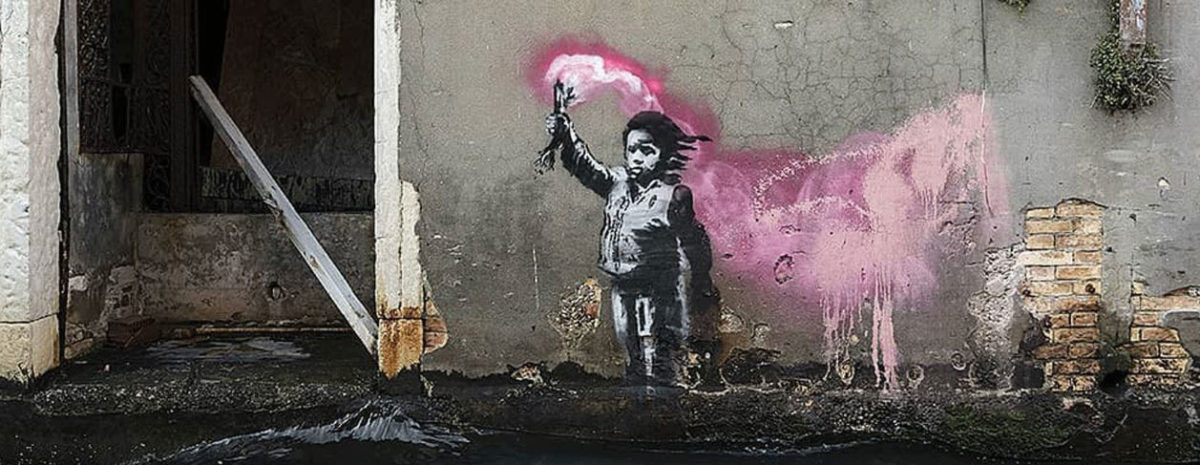 The mural depicts a migrant child holding a pink flare. Photo Credit: @banksy/Designboom.