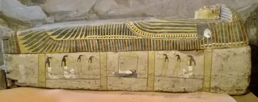 Uninscribed coffin with white coloring and brown columns; side view.