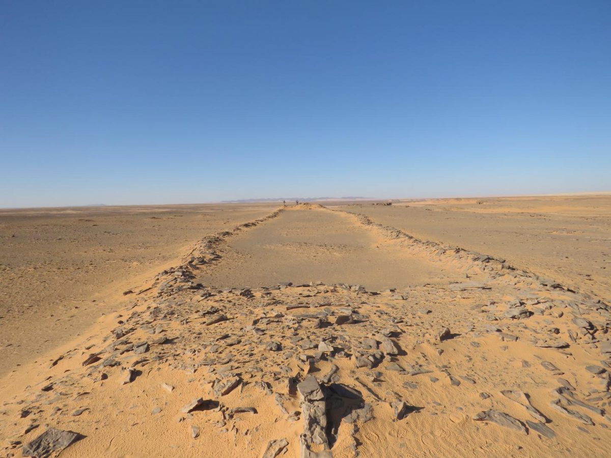 New archaeological research in Saudi Arabia documents hundreds of stone structures interpreted as monumental sites where early pastoralists carried out rituals. Image shows character of these structures as two platforms connected by low walls, note researchers at far end for scale. Credit: Huw Groucutt