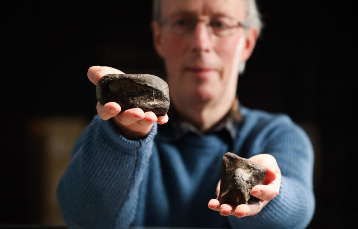 Dr Mike Simms, of National Museums NI, with the theropod tibia on the left and the Scelidosaurus femur on the right. Image Credit : National Museums NI