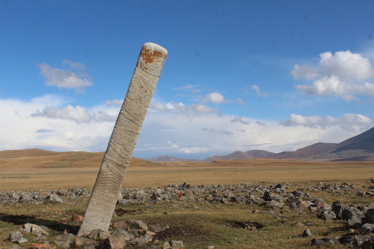 A leaning Deer Stone placed in front of dozens of small stone mounds containing ritually-sacrificed horse burials at the Bronze Age monument site of Ikh Tsagaanii Am, Bayankhongor Province, central Mongolia Credit: William Taylor