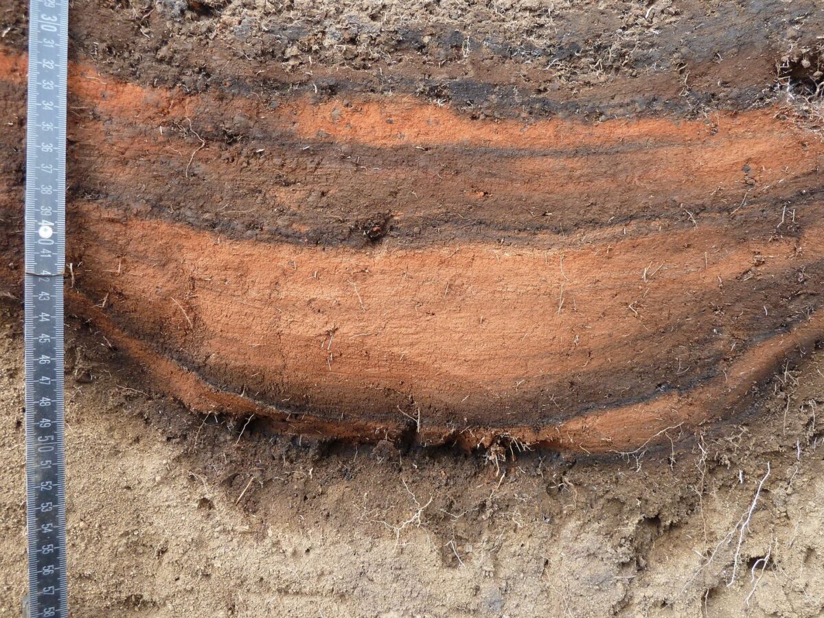 One of the pits filled with red pigment. The dark bands in the pit filling come from charred grass. © Andreas Mieth, Uni Kiel