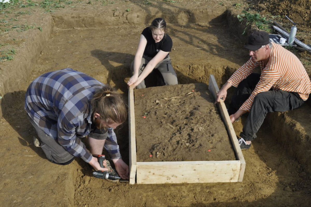 Preparing the grave to be taken out in one piece: Christoph Kühnbach of the regional heritage authority with the University of Tübingen’s Hannah Huber and Raiko Krauss (left to right). Credit: University of Tübingen