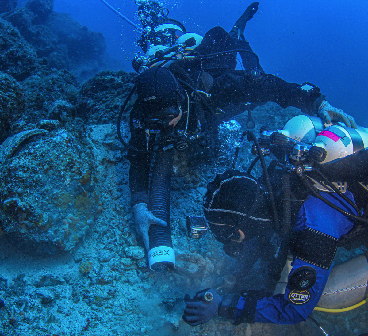 Archaeologist excavating in a trench of the shipwreck aided by a diver from the Coast Guard (image: MOCAS)