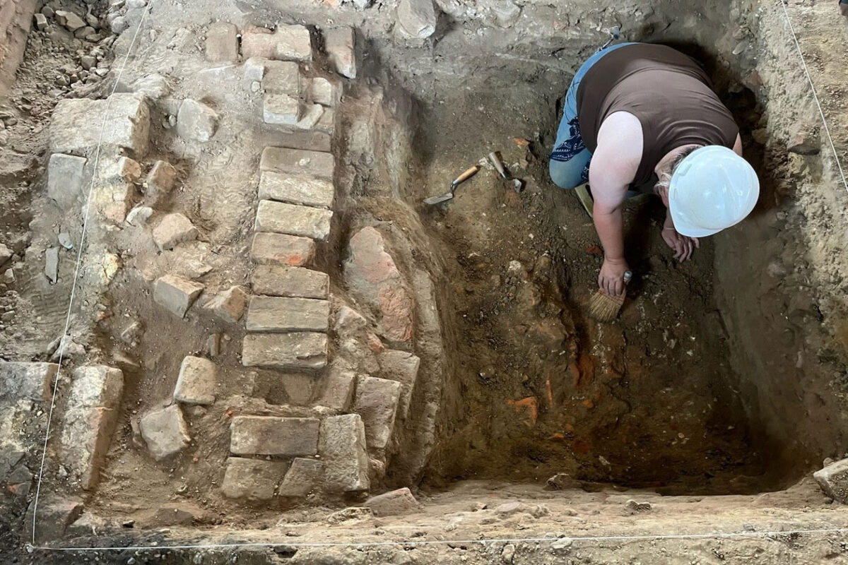 A W&M archaeologist works to expose a chimney base beneath Robert M. Gates Hall – believed to be part of the original 18th-century foundation of the Williamsburg Bray School.